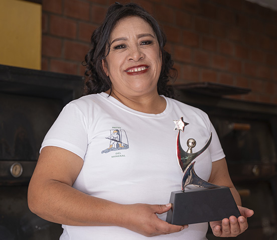 Teresa Medina ganadora del Premio Emprendedores 2024, luciendo su trofeo frente a un fondo azul.